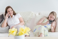 Photo of a mom on her cell phone and daughter texting